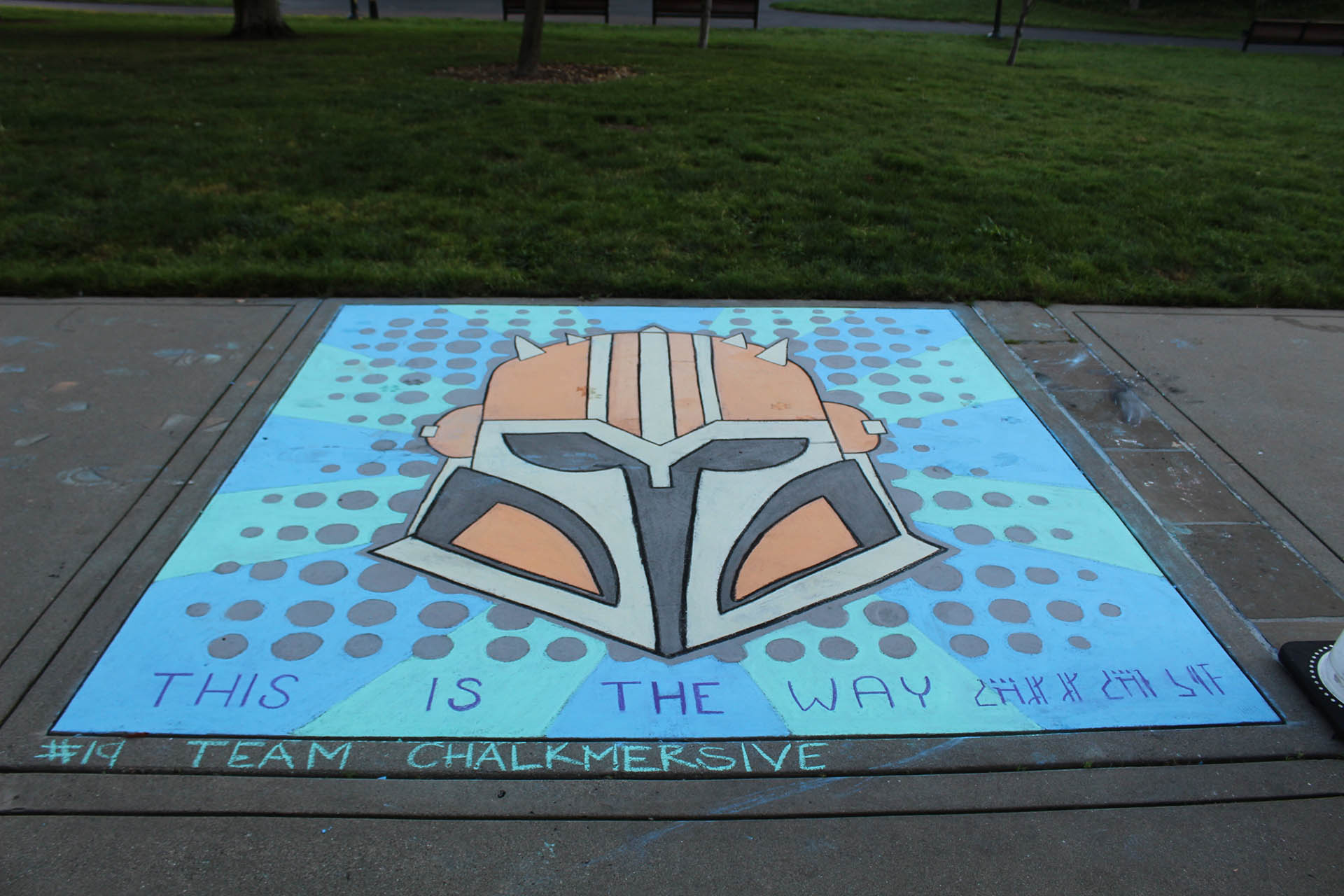 An entry from Lucasfilm Sidewalk Chalk Festival depicting the Armorer from The Mandalorian with "This Is The Way" written underneath.